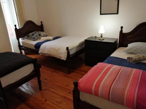 Habitación con 3 camas y mesa con lámpara. en LisBangla Guest House, en Lisboa