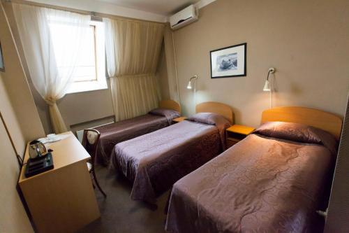 セルギエフ・ポサードにあるTsentralnaya Hotelのベッド3台と窓が備わるホテルルームです。