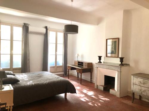 - une chambre avec un lit, un bureau et une cheminée dans l'établissement Beau 3 pièces 83 m2 au coeur du centre historique d'Aix en Provence, à Aix-en-Provence