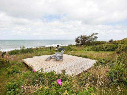 ジルレジェにある6 person holiday home in Gillelejeの海辺の木造遊歩道に座るベンチ