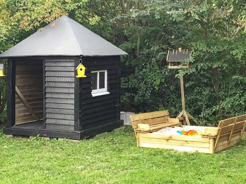 a black dog house and a bed in the grass at 9 person holiday home in Juelsminde in Sønderby