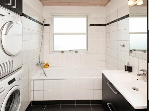 y baño con bañera, lavabo y lavadora. en 6 person holiday home in Karreb ksminde, en Karrebæksminde