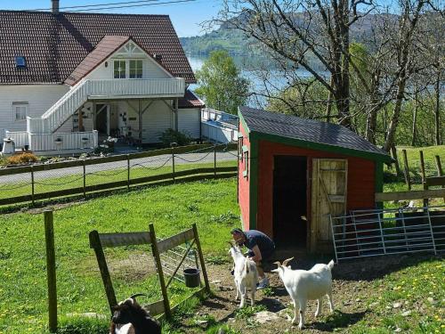 a man sitting in a barn with three goats at 6 person holiday home in Onarheim in Onarheim
