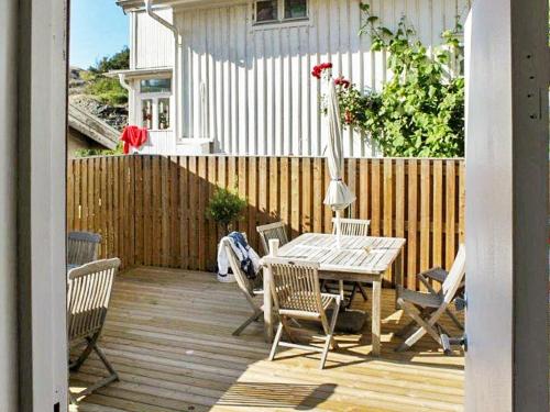eine Holzterrasse mit einem Tisch, Stühlen und einem Zaun in der Unterkunft 5 person holiday home in DYR N in Stora Dyrön