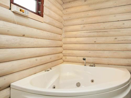 uma banheira branca numa casa de banho com paredes de madeira em 8 person holiday home in S by em Nordost