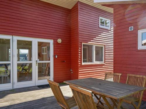 een houten tafel en stoelen buiten een rood huis bij 6 person holiday home in Gudhjem in Gudhjem