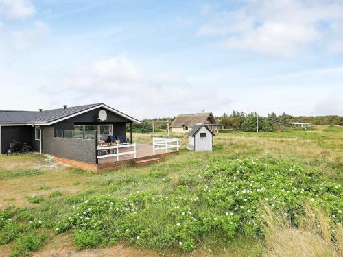 a house with a deck in a field at 8 person holiday home in Ringk bing in Ringkøbing