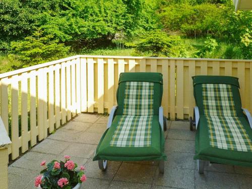 two green chairs sitting on a patio with a fence at 8 person holiday home in V ggerl se in Marielyst