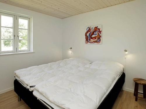 a white bed in a room with two windows at Holiday Home Den II in Læsø