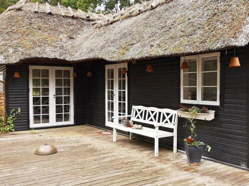 a black house with a white bench on a deck at 6 person holiday home in R dby in Rødby