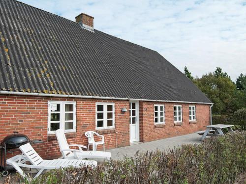een rood bakstenen huis met witte stoelen en een grill bij 5 person holiday home in R m in Toftum