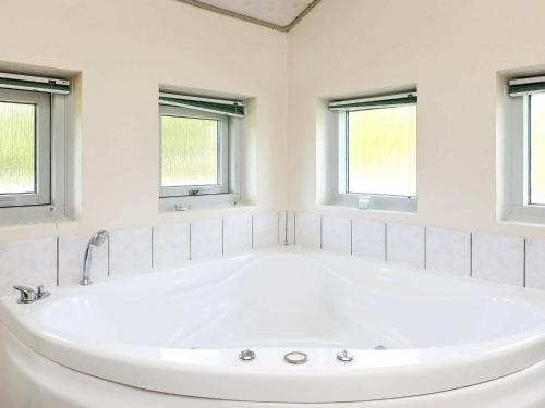 eine große weiße Badewanne im Bad mit Fenstern in der Unterkunft 8 person holiday home in Bl vand in Blåvand