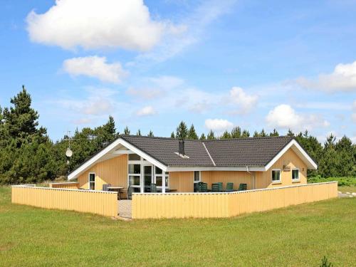 ein Haus mit einem Zaun davor in der Unterkunft 8 person holiday home in Bl vand in Blåvand