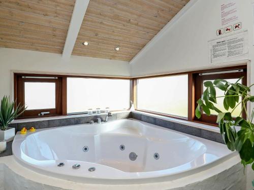 y baño con bañera grande y ventanas. en 8 person holiday home in Hj rring, en Lønstrup