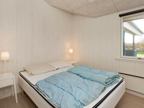 a white bedroom with a bed with blue sheets at 8 person holiday home in B rkop in Egeskov