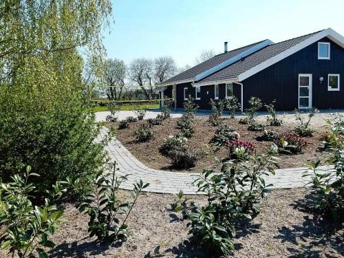 ノーポにある12 person holiday home in Nordborgの植物の黒い建物前の庭園
