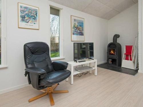 a living room with a black chair and a television at 8 person holiday home in B rkop in Egeskov