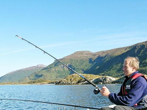 a man sitting on a boat holding a fishing rod at Three-Bedroom Holiday home in Gullesfjord in Flesnes