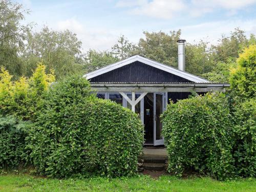 una pequeña casa con arbustos delante de ella en 8 person holiday home in Roslev, en Nøreng