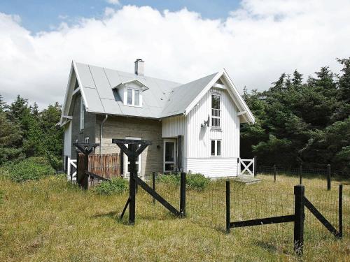 a small white house in a field with a fence at 5 person holiday home in Harbo re in Harboør