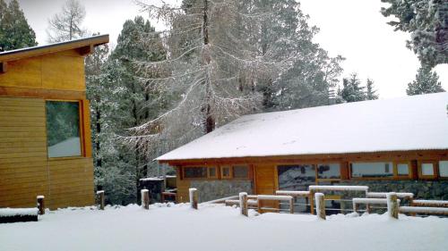 a log cabin with snow on the roof at Maria del Bosque Apart Hotel / Cabañas in San Carlos de Bariloche