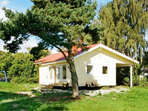 una pequeña casa blanca con un árbol en el patio en 3 person holiday home in FJ LKINGE en Fjälkinge