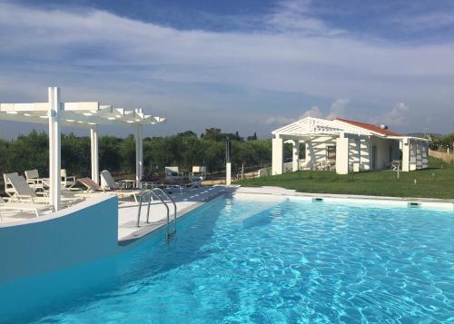 a swimming pool with chairs and a house at White Villas in Dhounaíika