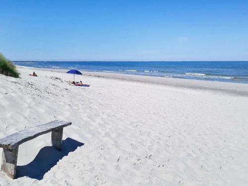 a wooden bench sitting on a beach with the ocean at 6 person holiday home in Jerup-By Traum in Jerup