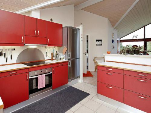a kitchen with red cabinets and a stainless steel refrigerator at 6 person holiday home in Hirtshals in Hirtshals
