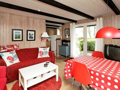 Tørresøにある4 person holiday home in Otterupのリビングルーム(赤いソファ、テーブル付)
