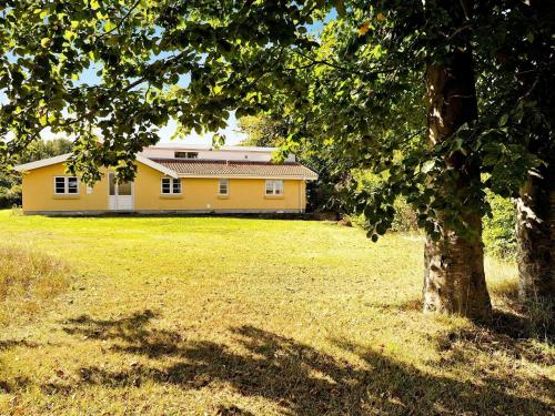 una casa gialla con un albero in un campo di 10 person holiday home in B rkop a Egeskov