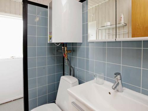 uma casa de banho em azulejos azuis com um WC e um lavatório em Three-Bedroom Holiday home in Hals 38 em Hals