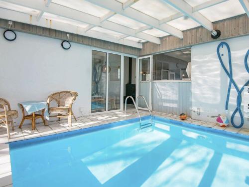 a swimming pool with a table and chairs next to a house at 7 person holiday home in rsted in Kare