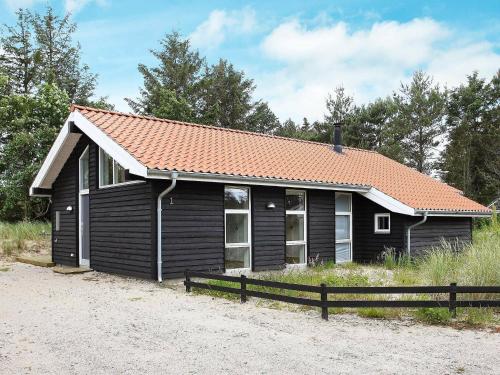 スケーエンにある6 person holiday home in Skagenのオレンジ色の屋根の小さな黒い家