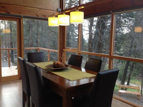a dining room with a table and chairs and windows at Maria del Bosque Apart Hotel / Cabañas in San Carlos de Bariloche