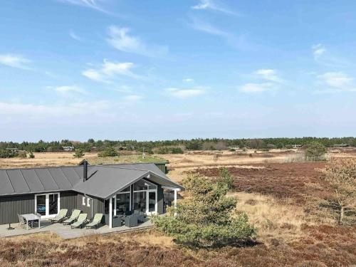 a house in a field with chairs on a porch at 8 person holiday home in R m in Bolilmark