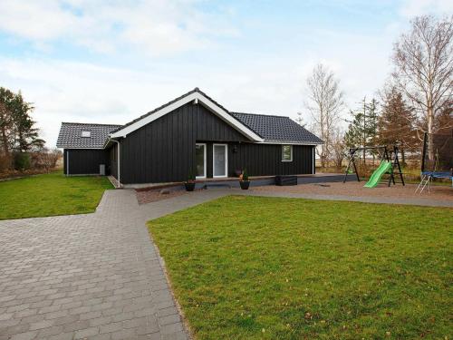a black house with a playground in front of it at Luxury Retreat with Pool - By Traum Ferienwohnungen in Gørlev