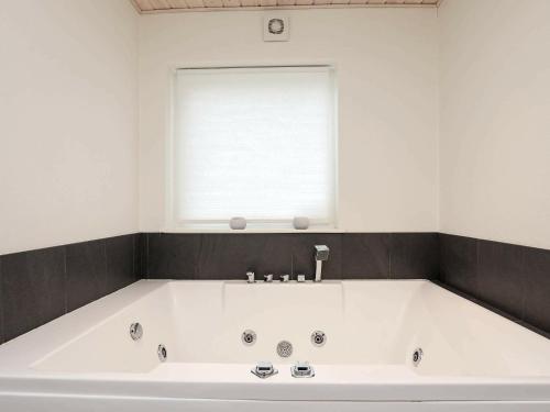 a large white tub in a bathroom with a window at 9 person holiday home in Hj rring in Lønstrup
