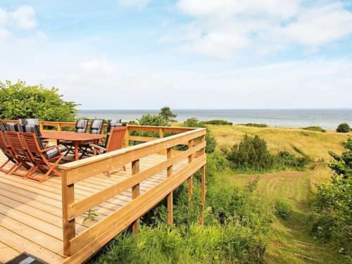 a wooden deck with chairs and a table on the beach at 8 person holiday home in Asn s in Asnæs