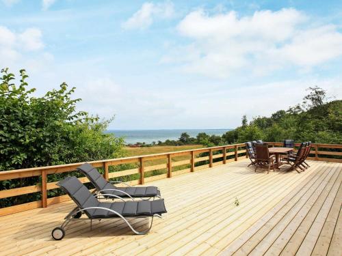 a wooden deck with chairs and a table on it at 8 person holiday home in Asn s in Asnæs