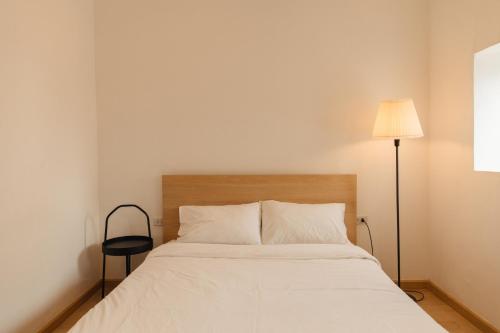 バンコクにあるホステル ウルビーのベッドルーム(白いベッド1台、ランプ付)