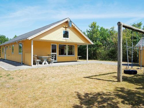 una pequeña casa amarilla con una mesa de picnic en un patio en 6 person holiday home in Ulfborg en Ulfborg