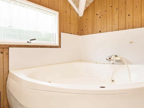eine weiße Badewanne im Bad mit Fenster in der Unterkunft 7 person holiday home in Bl vand in Ho