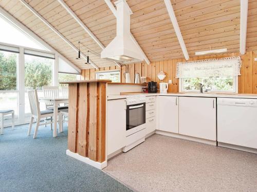 ホにある7 person holiday home in Bl vandの白いキャビネット、テーブルと椅子付きのキッチンが備わります。