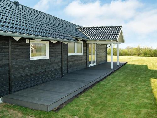 uma casa com um telhado preto e um deque em 10 person holiday home in Sydals em Vibøge