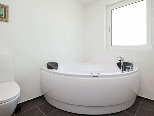 a white bath tub in a bathroom with a toilet at Holiday home Øster Assels in Tjørneholm