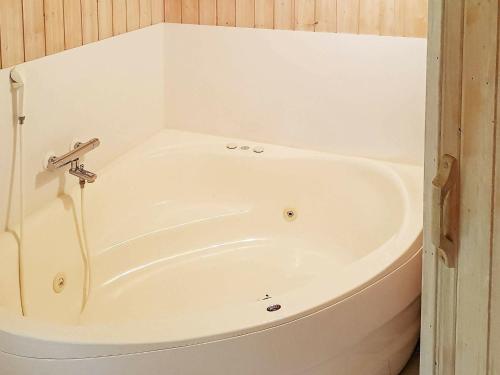 a white bath tub in a bathroom with wooden walls at 6 person holiday home in Oksb l in Oksbøl