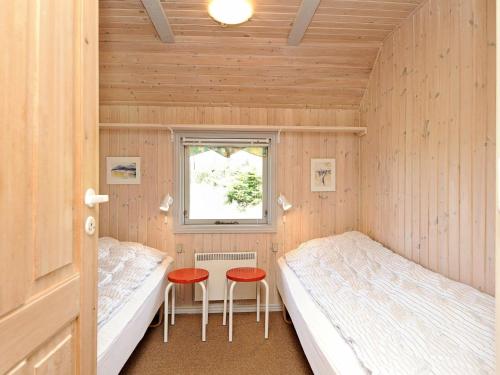 ブラーバンドにあるHoliday Home Sydslugenのベッド2台とスツール2台が備わる小さなお部屋です。