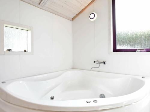 La salle de bains blanche est pourvue d'une baignoire blanche et d'une fenêtre. dans l'établissement 8 person holiday home in Oksb l, à Vejers Strand