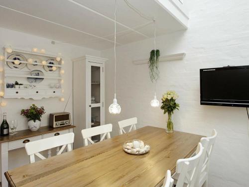 a dining room with a wooden table and white chairs at 5 person holiday home in Bl vand in Blåvand
